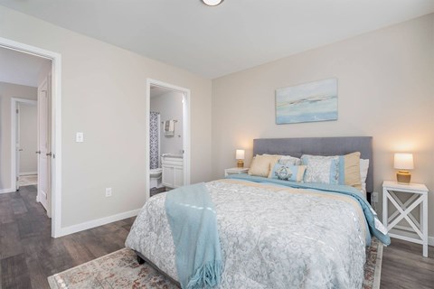 A bedroom with a bed, a nightstand, and a painting on the wall.