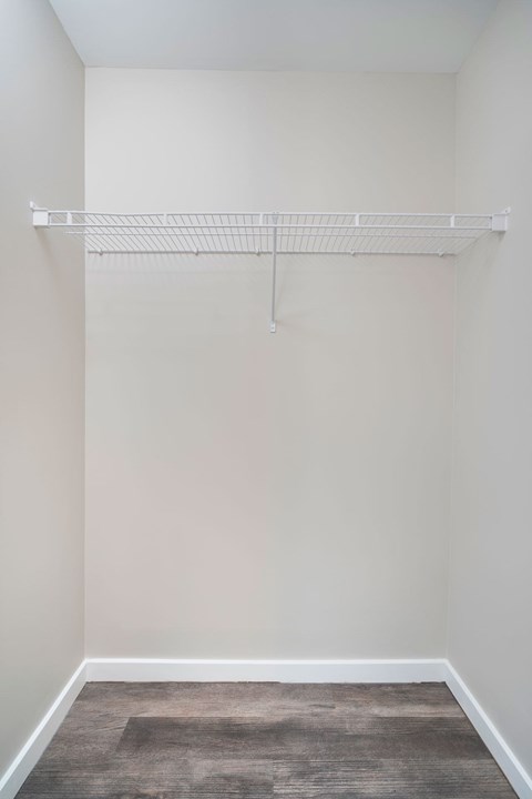 Empty room with a white shelf and a rug on the floor.