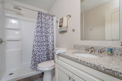A white bathroom with a toilet, sink, and shower.