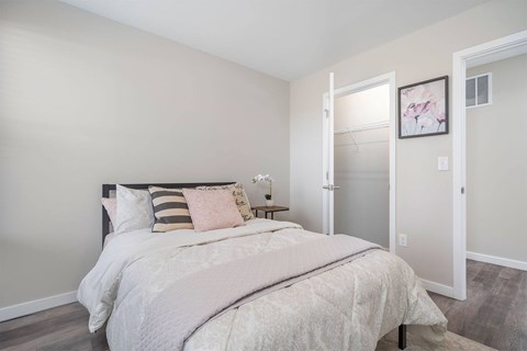 A bedroom with a large bed and a nightstand with a lamp.