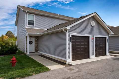 A house with a grey siding and a red fire hydrant in front.