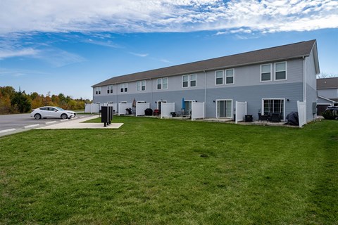 A white car is parked in front of a grey building.