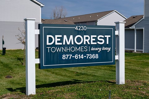 A sign for Demorest Townhomes by Luxury Living is displayed in front of the townhomes