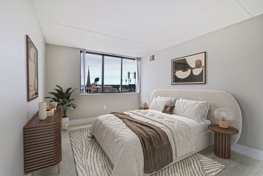 A bedroom with a large bed and a window overlooking a cityscape.