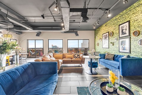 A living room with a blue couch and a glass coffee table.
