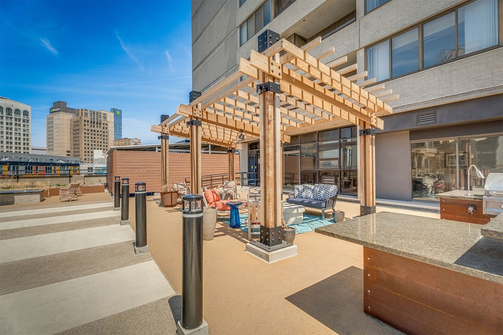 A wooden pergola is situated on a patio with a concrete counter.