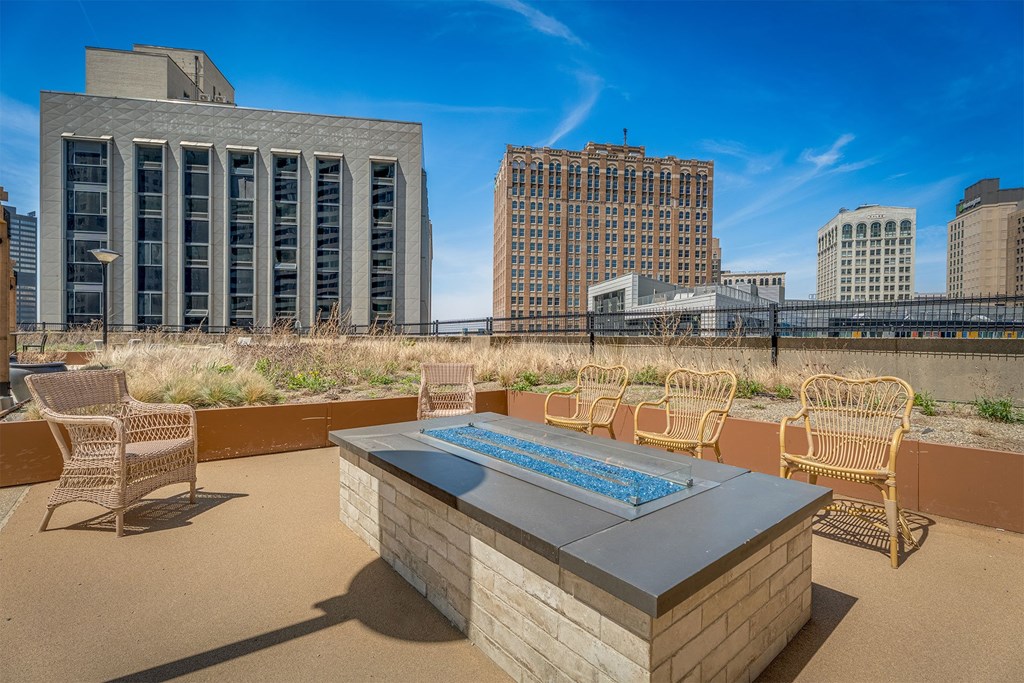 A rooftop patio with a hot tub and chairs.