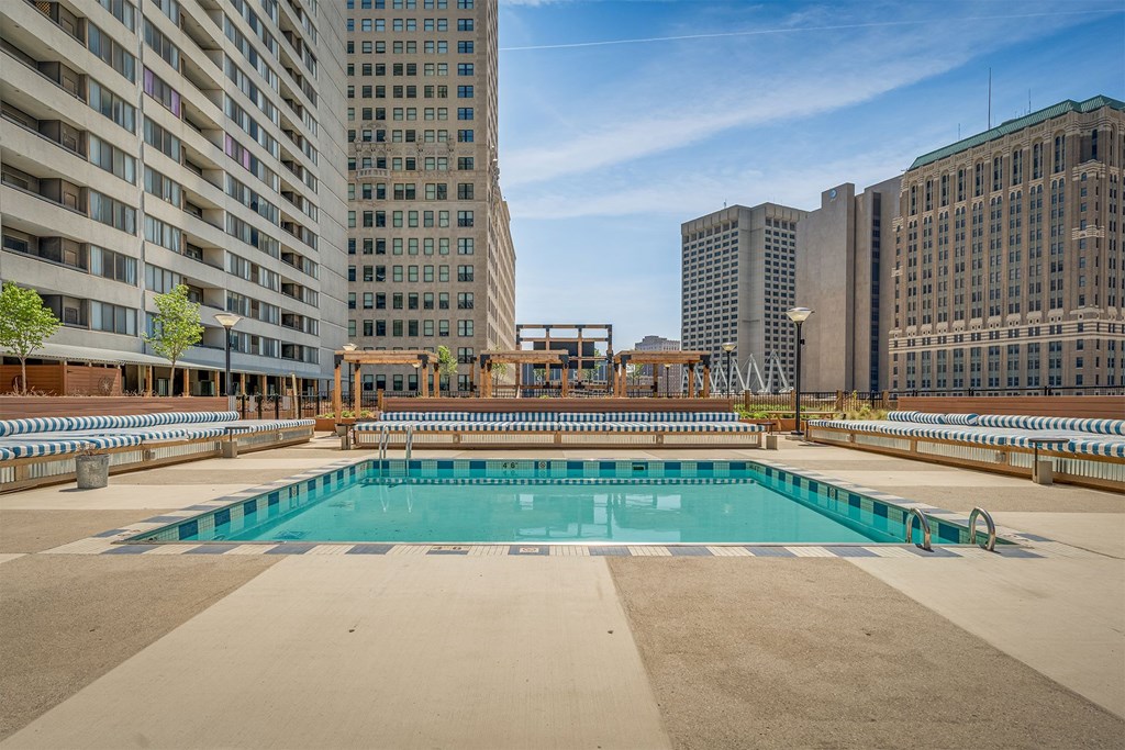 A large swimming pool on a rooftop with buildings in the background.