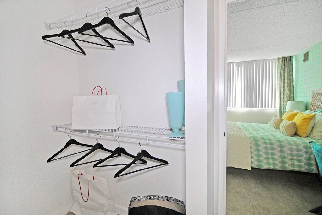 a bedroom with a closet with hooks and a shelf with shoes on it