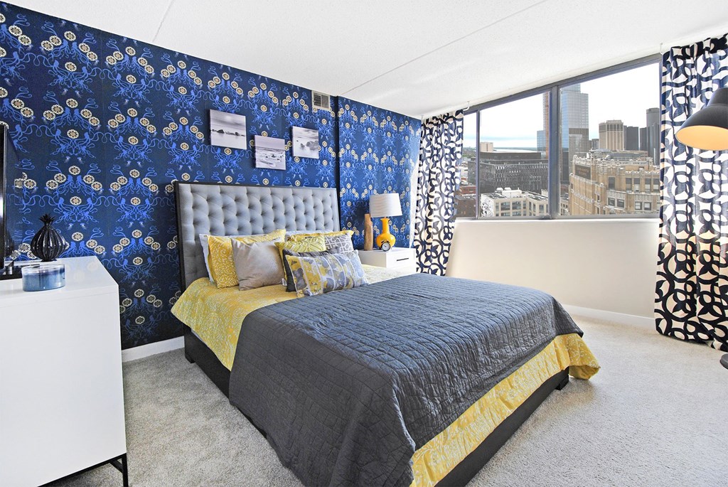 a bedroom with blue wallpaper and a bed with a yellow blanket