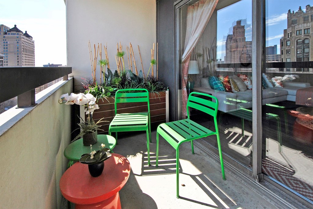 a small balcony with two green chairs and a table