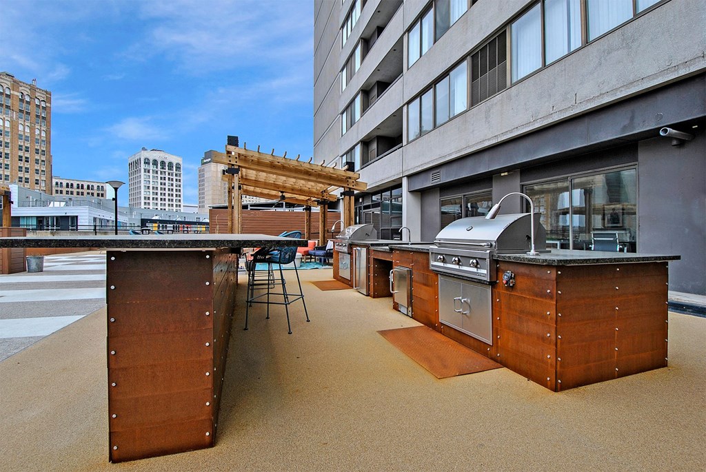an outdoor kitchen with stainless steel appliances and wooden cabinets on a building