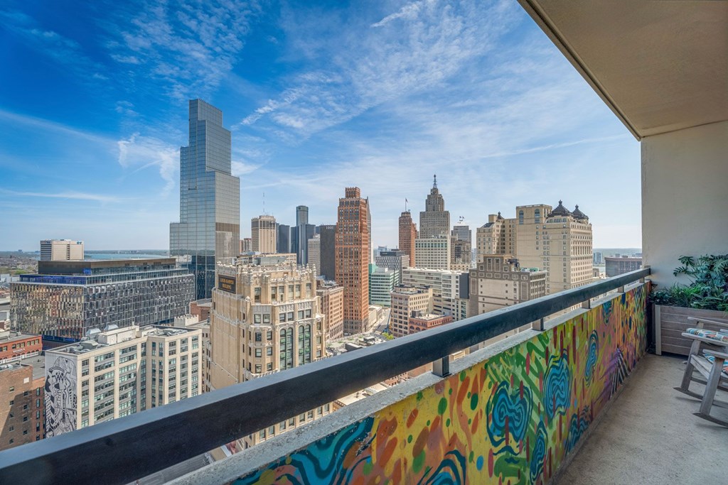 A balcony with a colorful mural overlooks a city skyline.