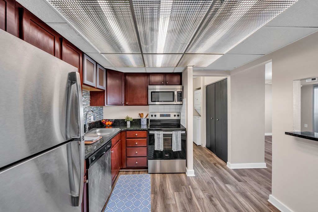 A kitchen with a refrigerator, microwave, oven, and sink.