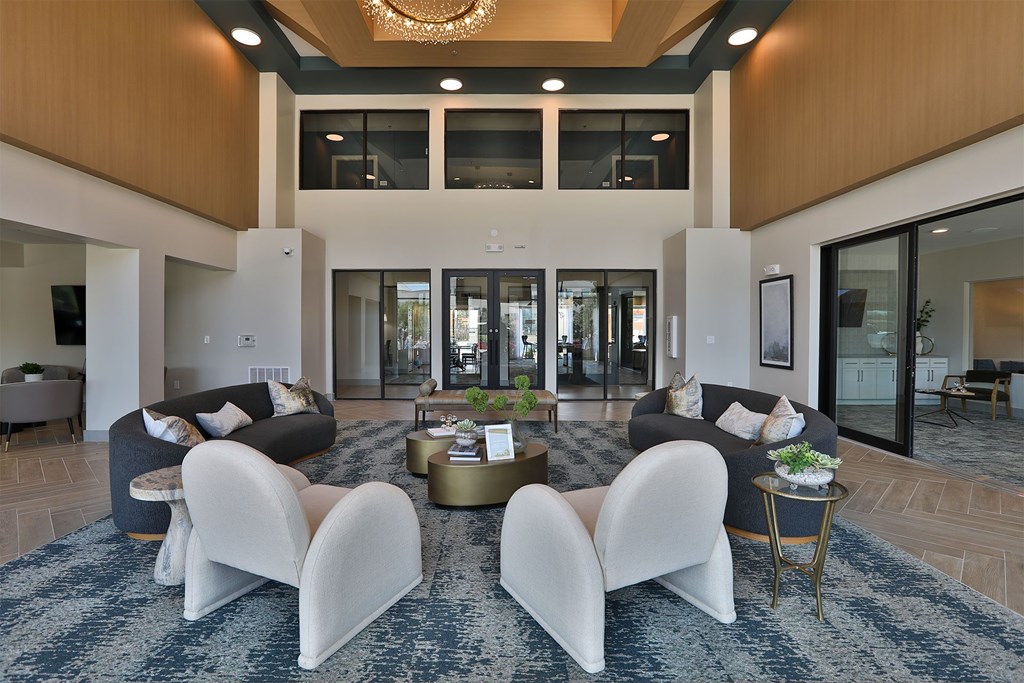 A modern living room with a large rug and white chairs.