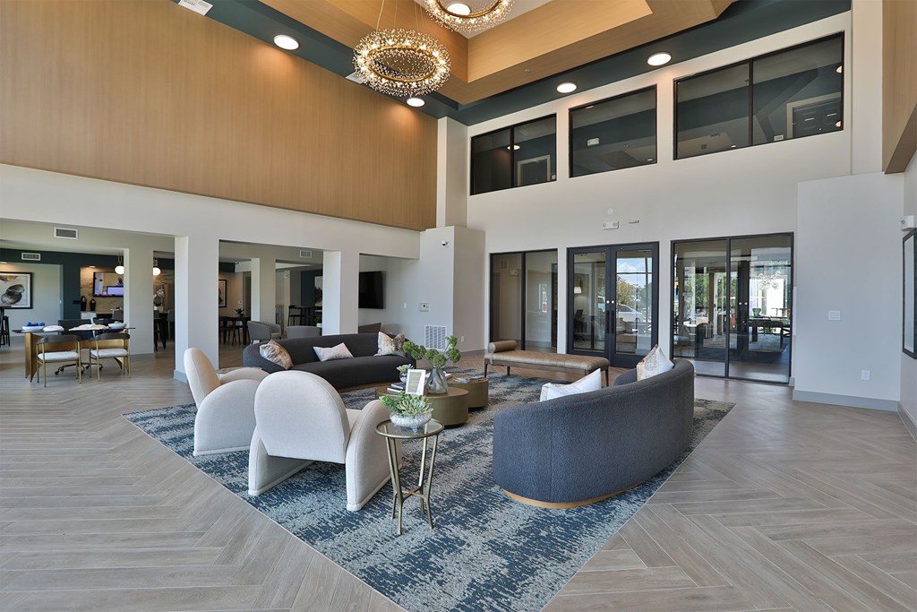 A spacious living room with a grey sofa and a wooden floor.