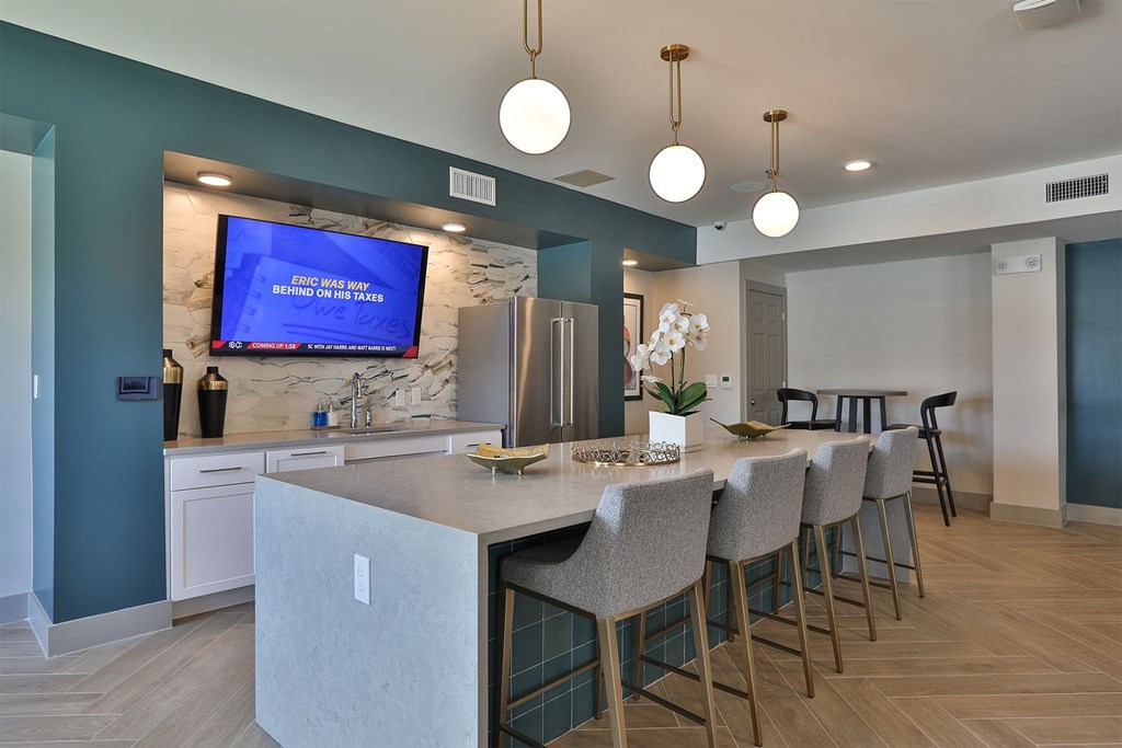 A modern kitchen with a bar area and a television screen mounted on the wall.