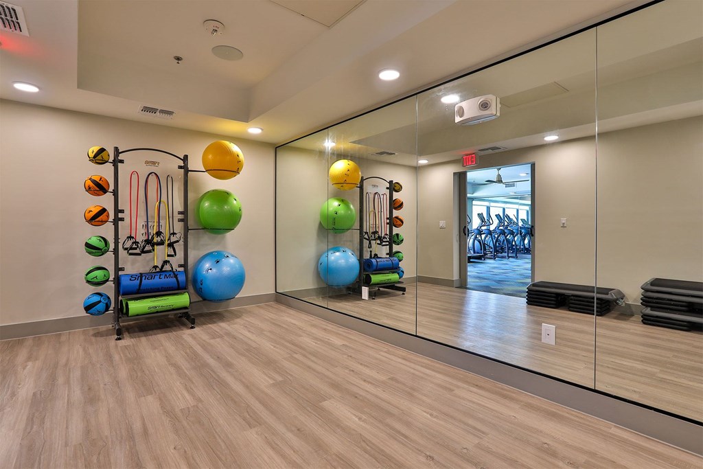 A gym with exercise equipment and a mirror on the wall.