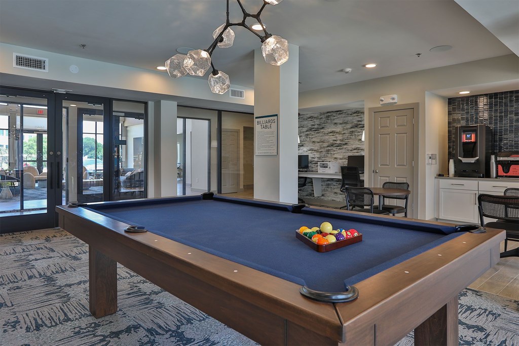 A pool table with a blue cloth and a set of balls on it.