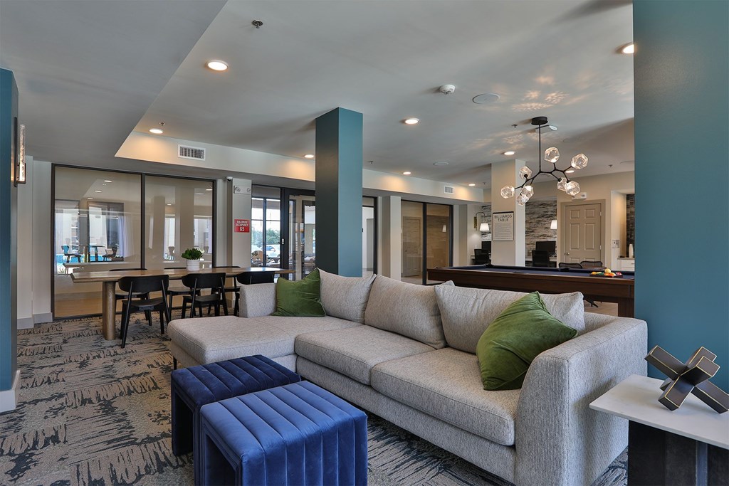 A living room with a grey couch and a blue ottoman.