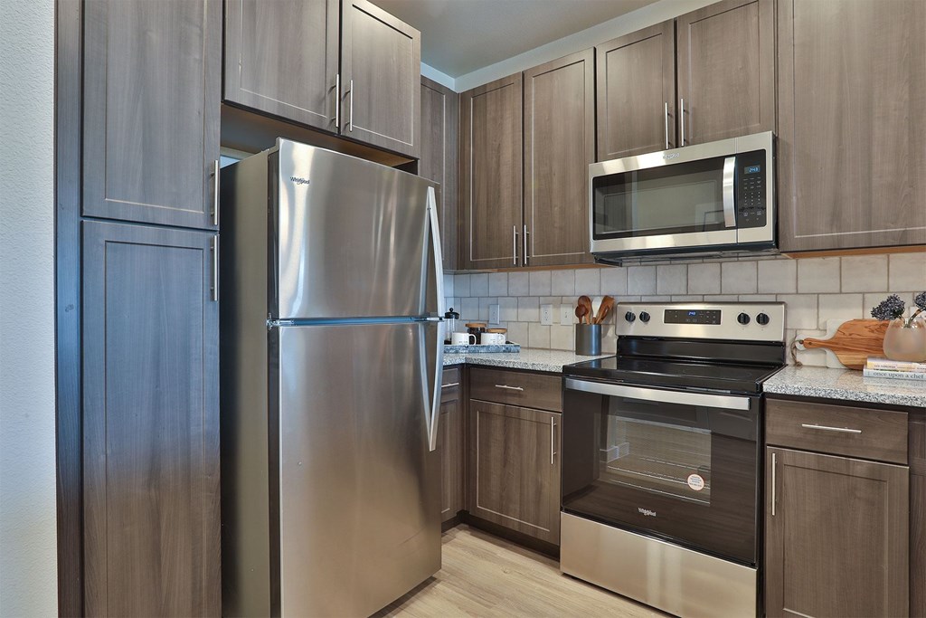A kitchen with a stainless steel refrigerator, microwave, and oven.