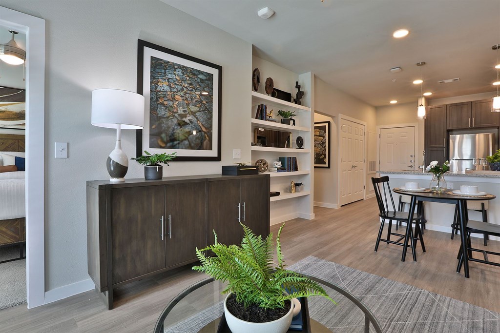 A modern living room with a wooden cabinet, a potted plant, and a framed picture on the wall.