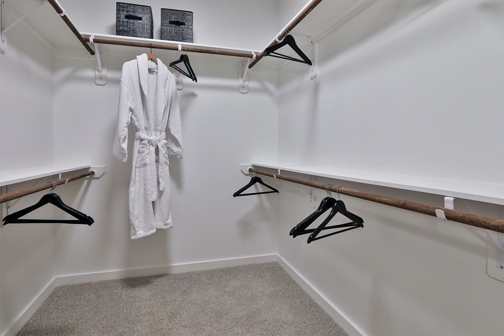 A white bathroom with a white robe hanging on a hanger.