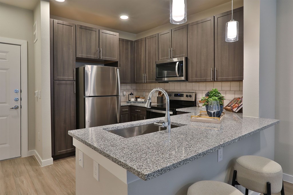 A kitchen with a granite countertop and stainless steel appliances.
