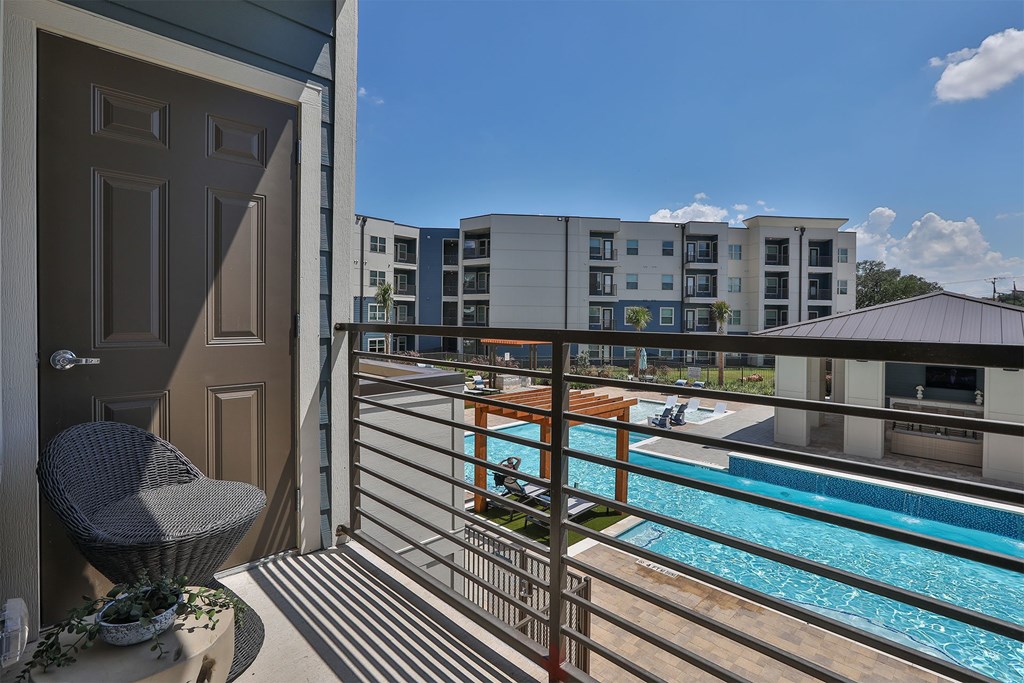 A balcony with a chair and a pool in the background.