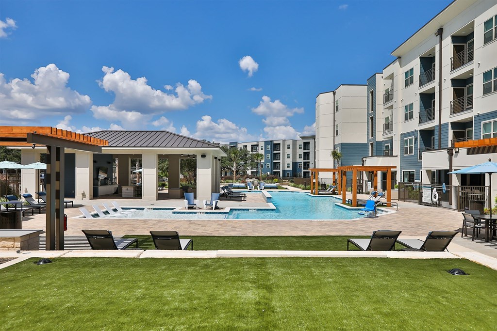 A swimming pool surrounded by lounge chairs and a building in the background.