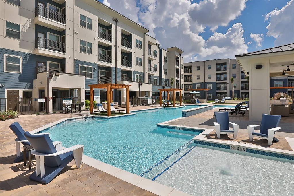 A swimming pool surrounded by chairs and buildings.