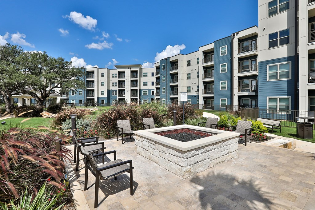 A sunny day at a residential complex with a fountain in the middle of a patio.