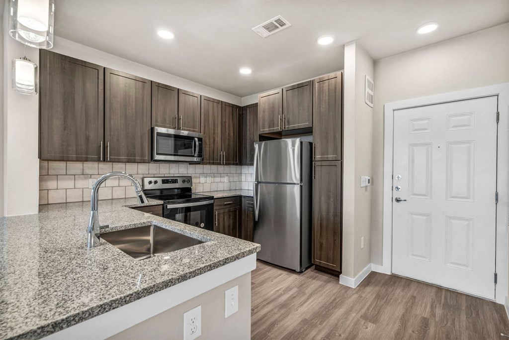 a kitchen with a granite counter top and a stainless steel refrigerator