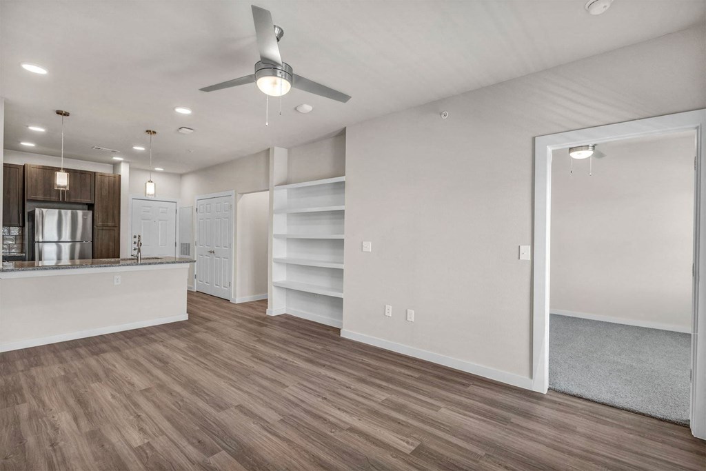 a living room with a kitchen and a ceiling fan
