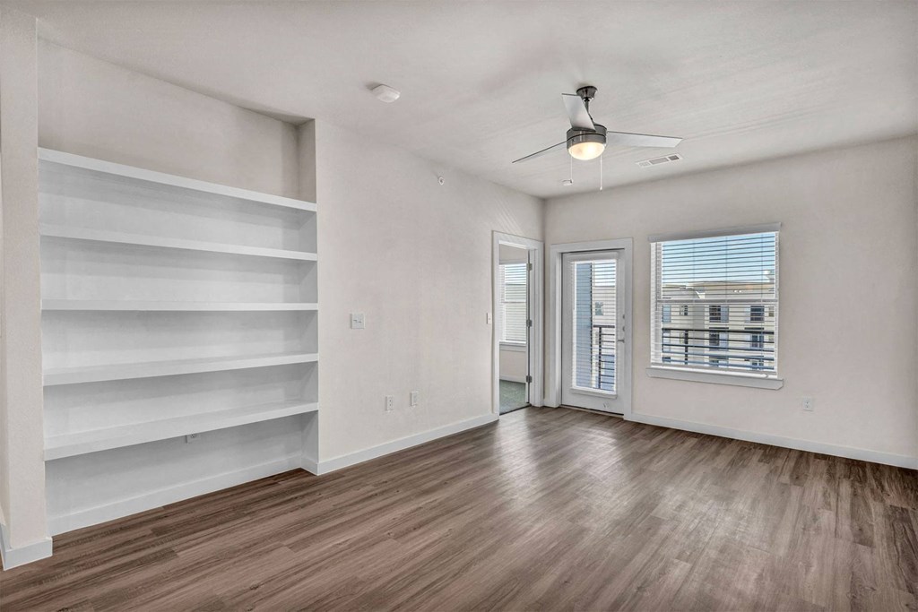 an empty living room with white walls and wood floors and a window with white shelves