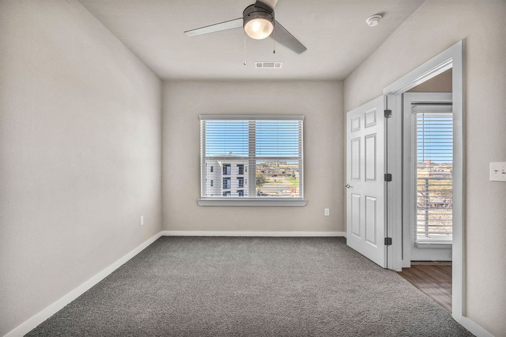 an empty bedroom with a ceiling fan and a window