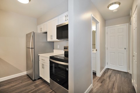 A kitchen with a refrigerator, microwave, oven, and cabinets.