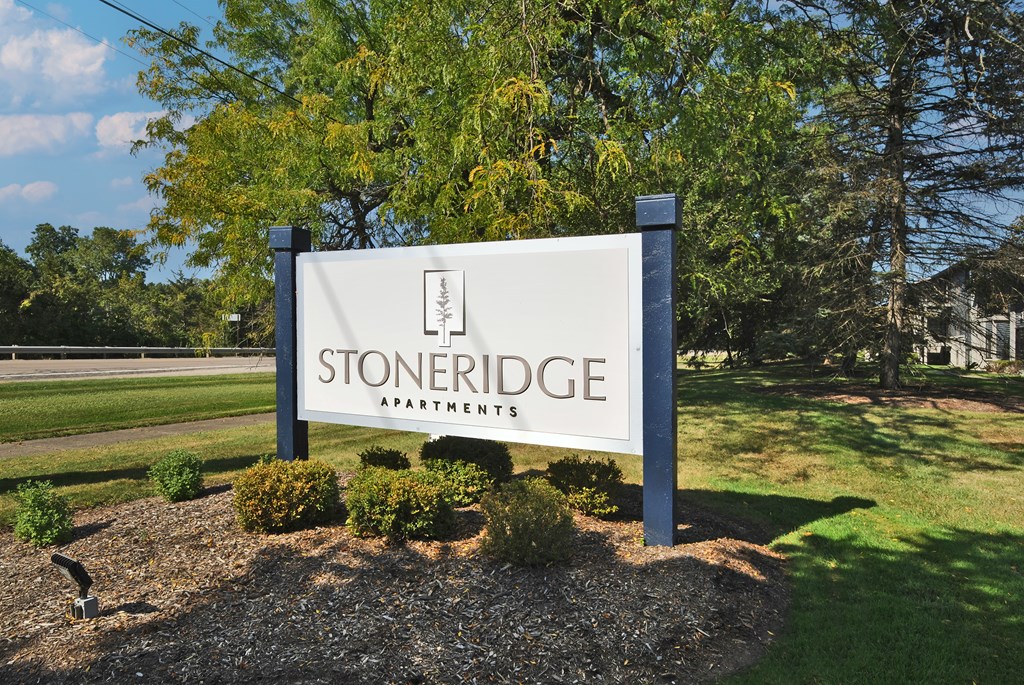 A sign for Stoneridge Apartments is displayed in front of a grassy area.