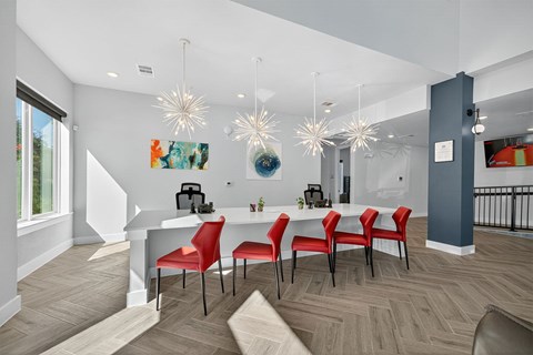 A dining room with a white table and red chairs.