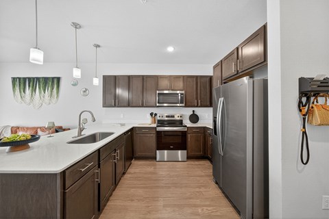A modern kitchen with a refrigerator, sink, and oven.