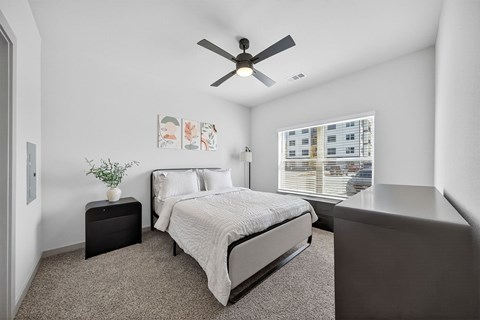 A bedroom with a bed, nightstand, and a ceiling fan.
