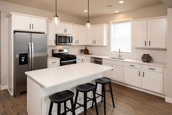 a large white kitchen with stainless steel appliances and a white counter top
