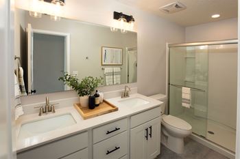 a white bathroom with two sinks and a shower