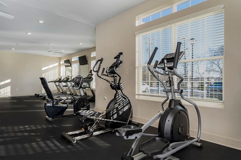 A gym with a row of exercise bikes and elliptical machines.