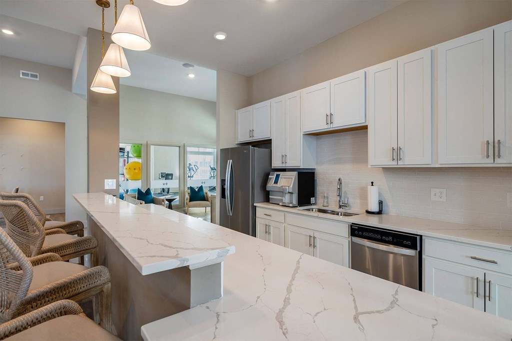 A kitchen with white cabinets and a marble countertop.