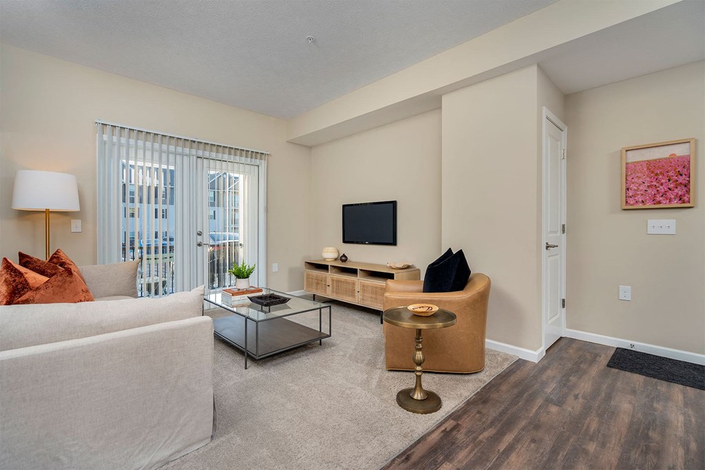 A living room with a white couch, a coffee table, and a television.