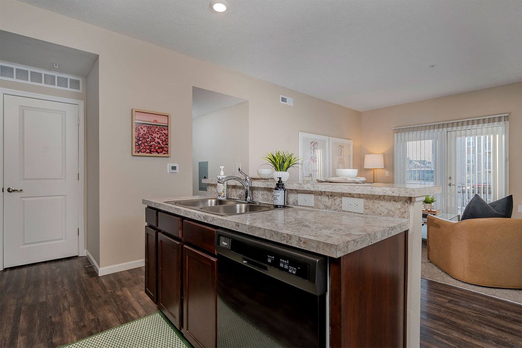 A kitchen with a marble countertop and dark wood cabinets.