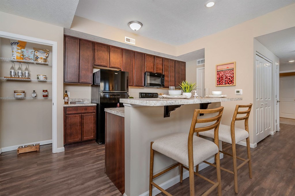 A kitchen with wooden cabinets and a black refrigerator.