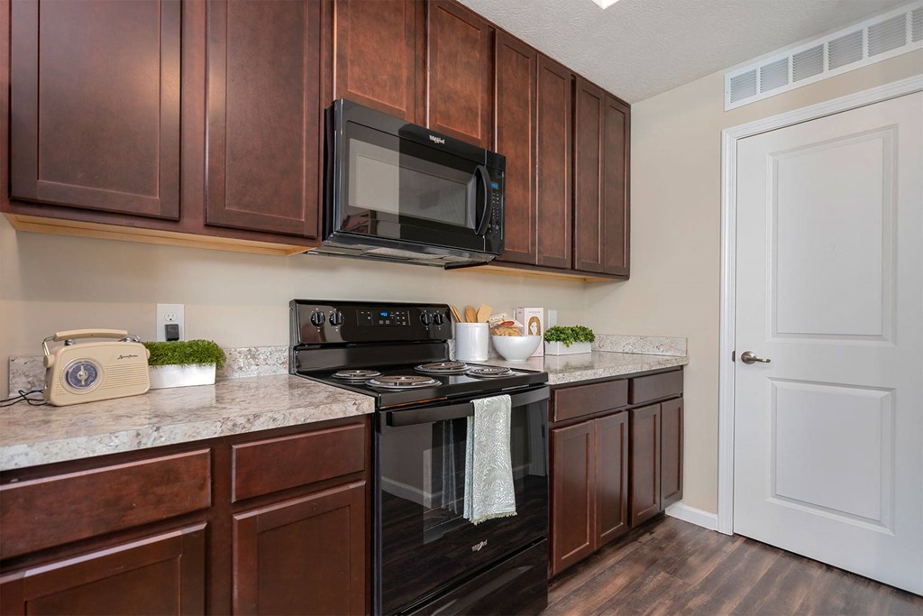 A kitchen with brown cabinets and a black stove top oven.