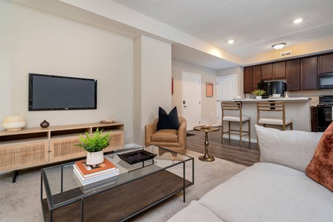 A modern living room with a flat screen TV, a glass coffee table, and a comfortable seating area.